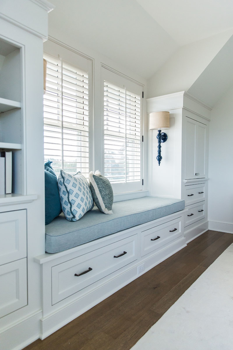 window seat in primary bedroom with built in shelving and drawers