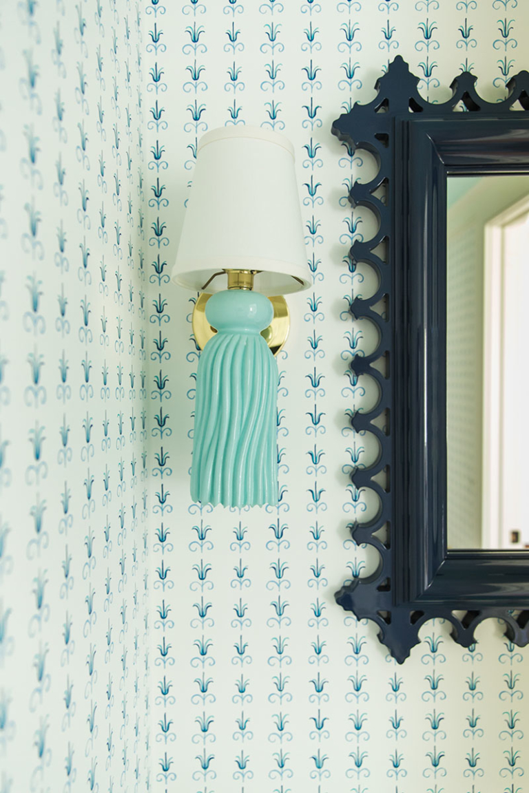 powder room with colorful wallpaper, sconce lighting and mirror
