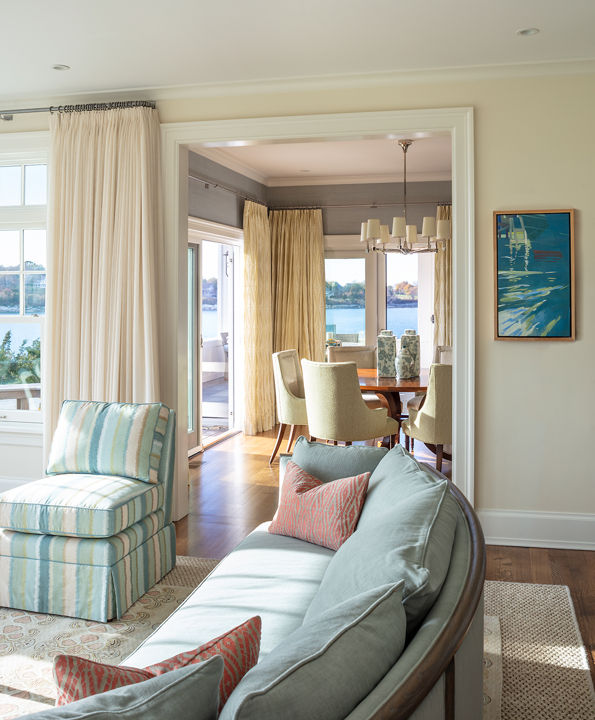 Coastal living room with sofa, chair and custom window treatments. Open to dining room.