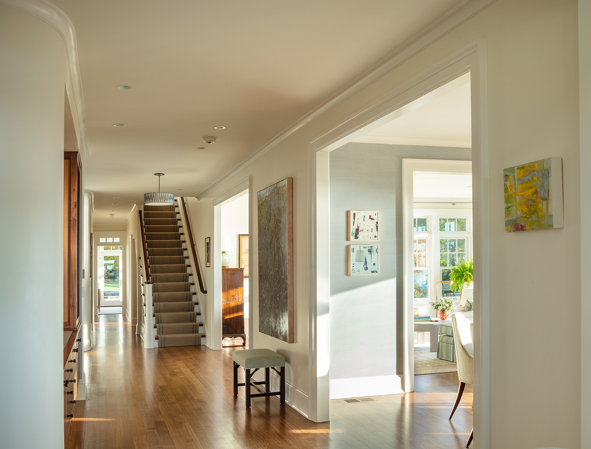 entryway with stairs and views into dining room. Art and seating areas.