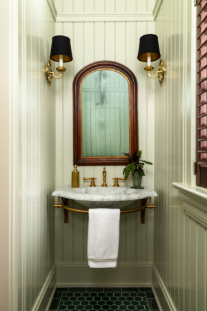 powder room with wallpaper and arched mirror