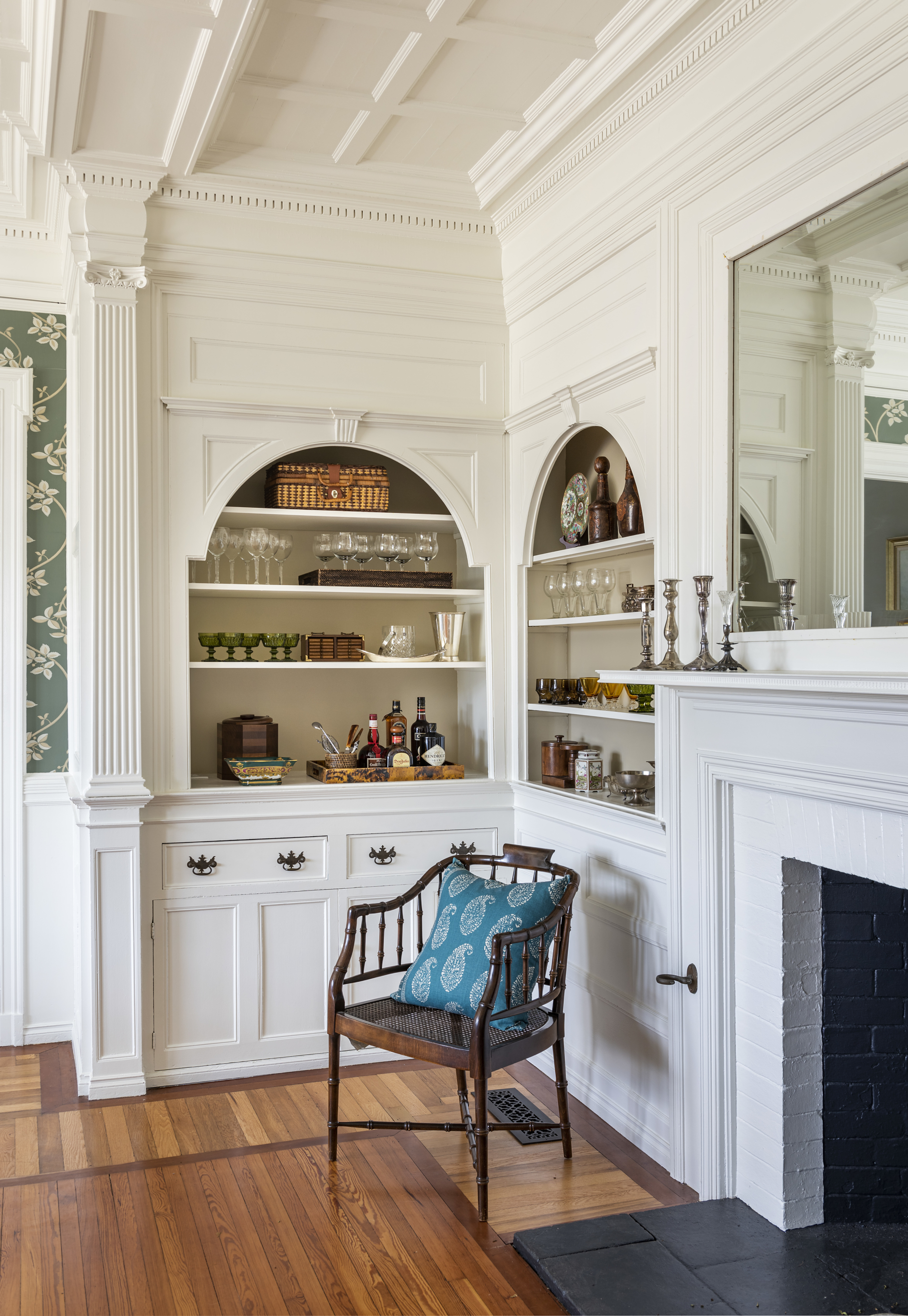 Corner of dining room with built-in shelves and chair by fireplace
