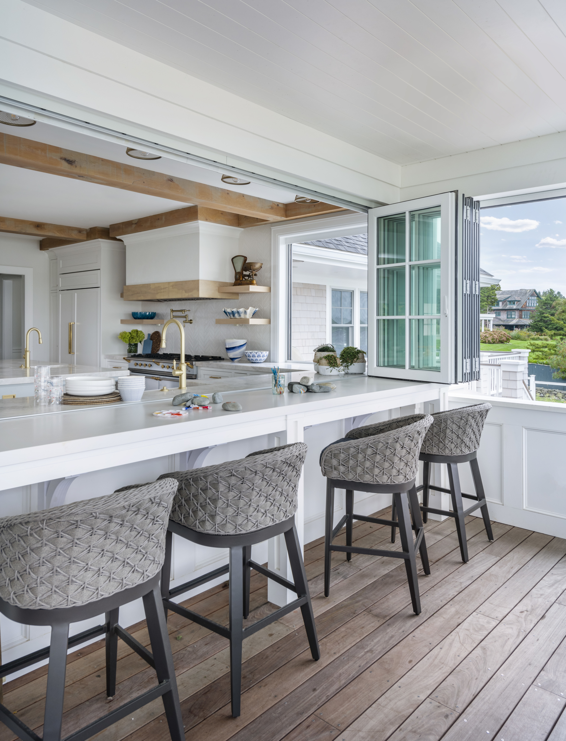 Exterior porch with accordion windows that open to interior kitchen. Outdoor furniture.