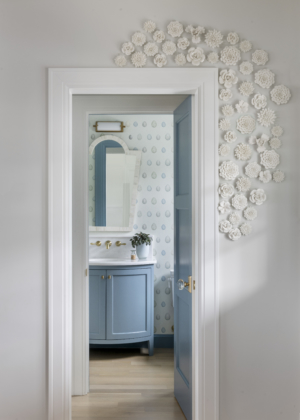 Powder room with colorful wallpaper and original art on the doorframe. Fun powder room.