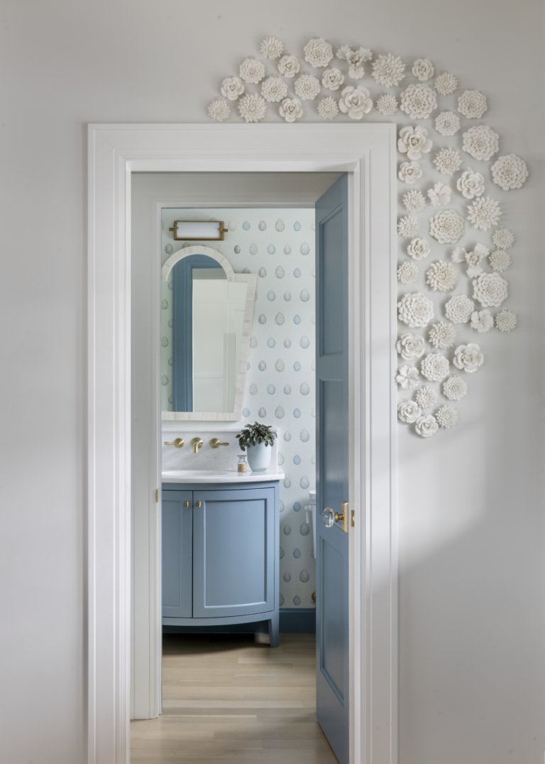 Powder room with colorful wallpaper and original art on the doorframe. Fun powder room.