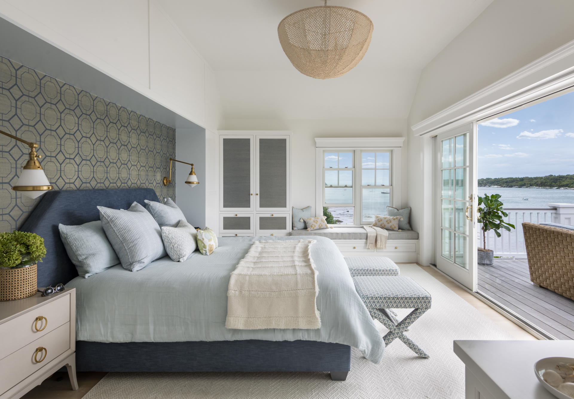 The interior design of the primary bedroom overlooks the ocean and a walkout deck. Bedroom with window seat and french doors opening to upper level deck. Custom furniture.