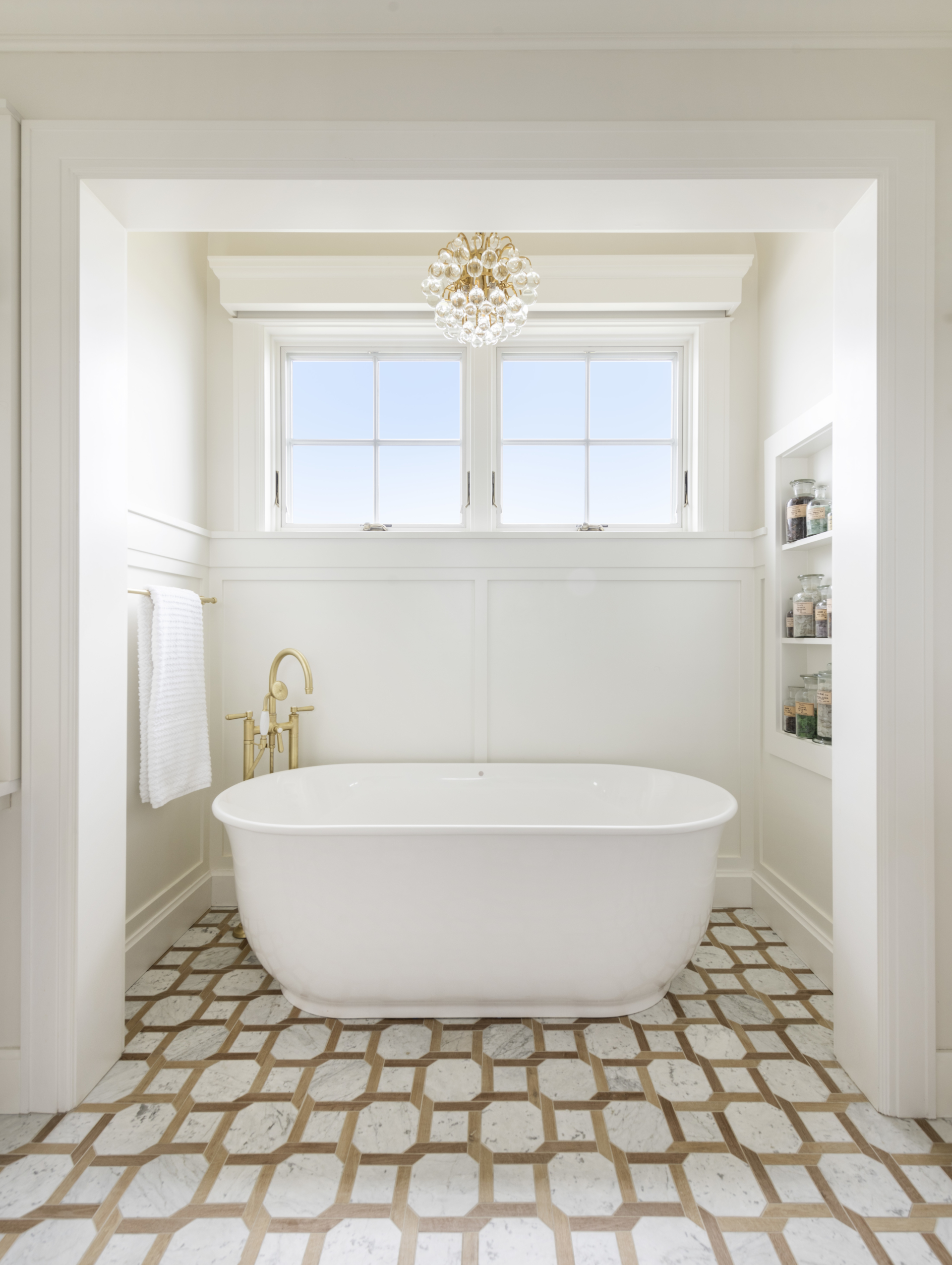 Primary bathtub in a coastal home. Large soaking tub with chandelier lighting. Primary Bathroom.