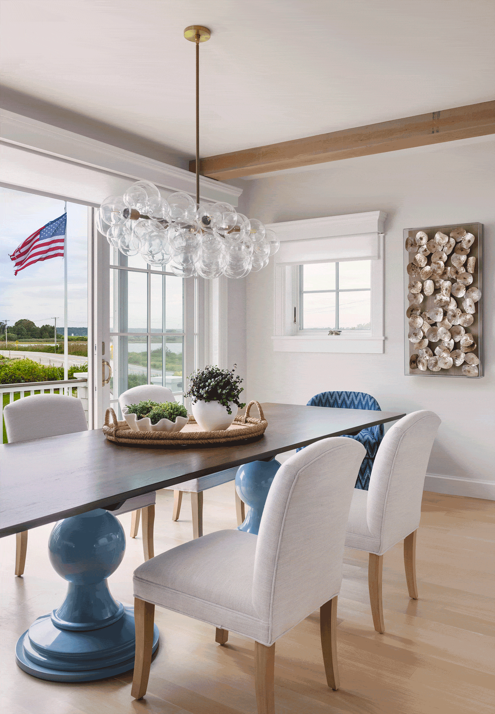 A coastal beach house dining room with a Dunes and Duchess table and flag blowing in the ocean breeze