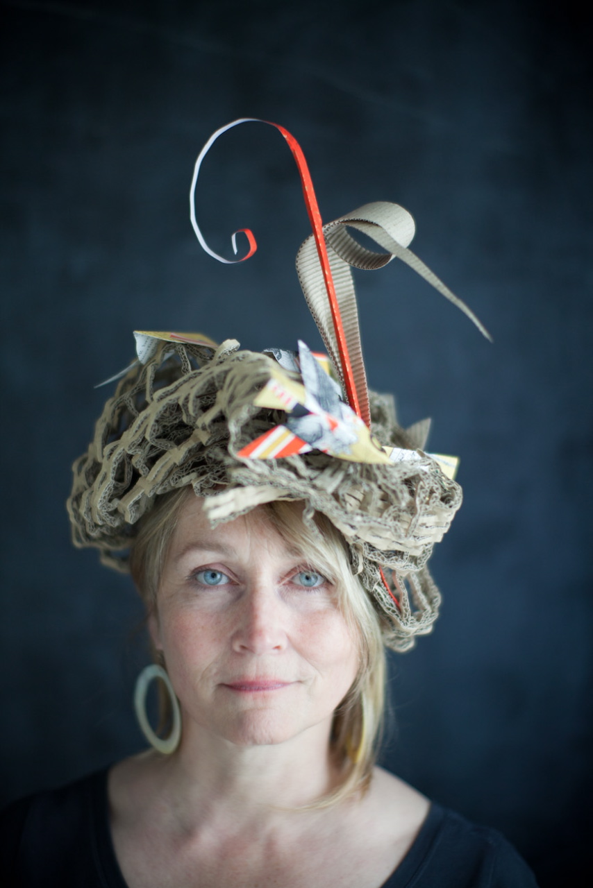 Artist Alyn Carlson wearing a paper hat made of packing materials