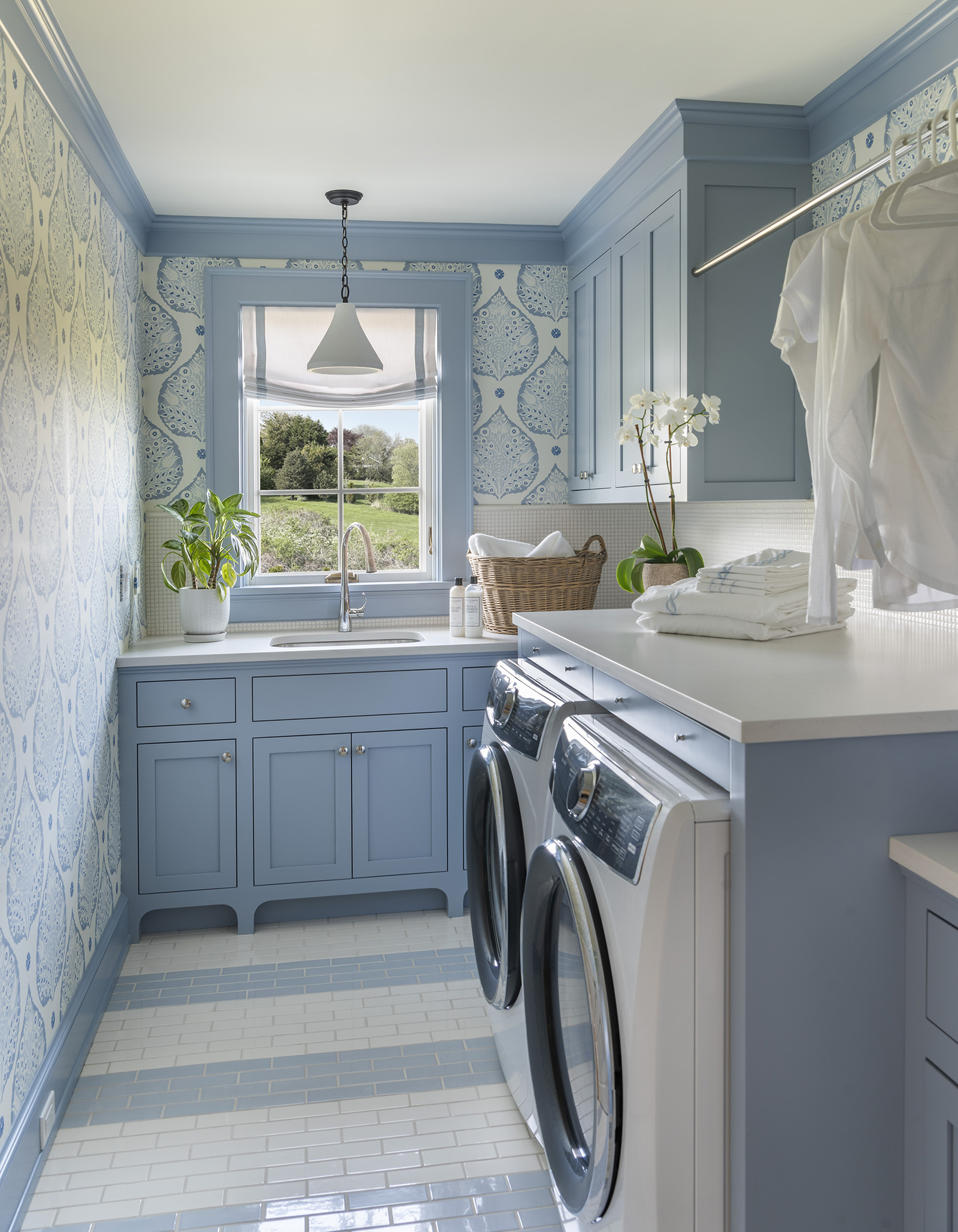A blue wallpapered laundry room with a modern coastal vibe