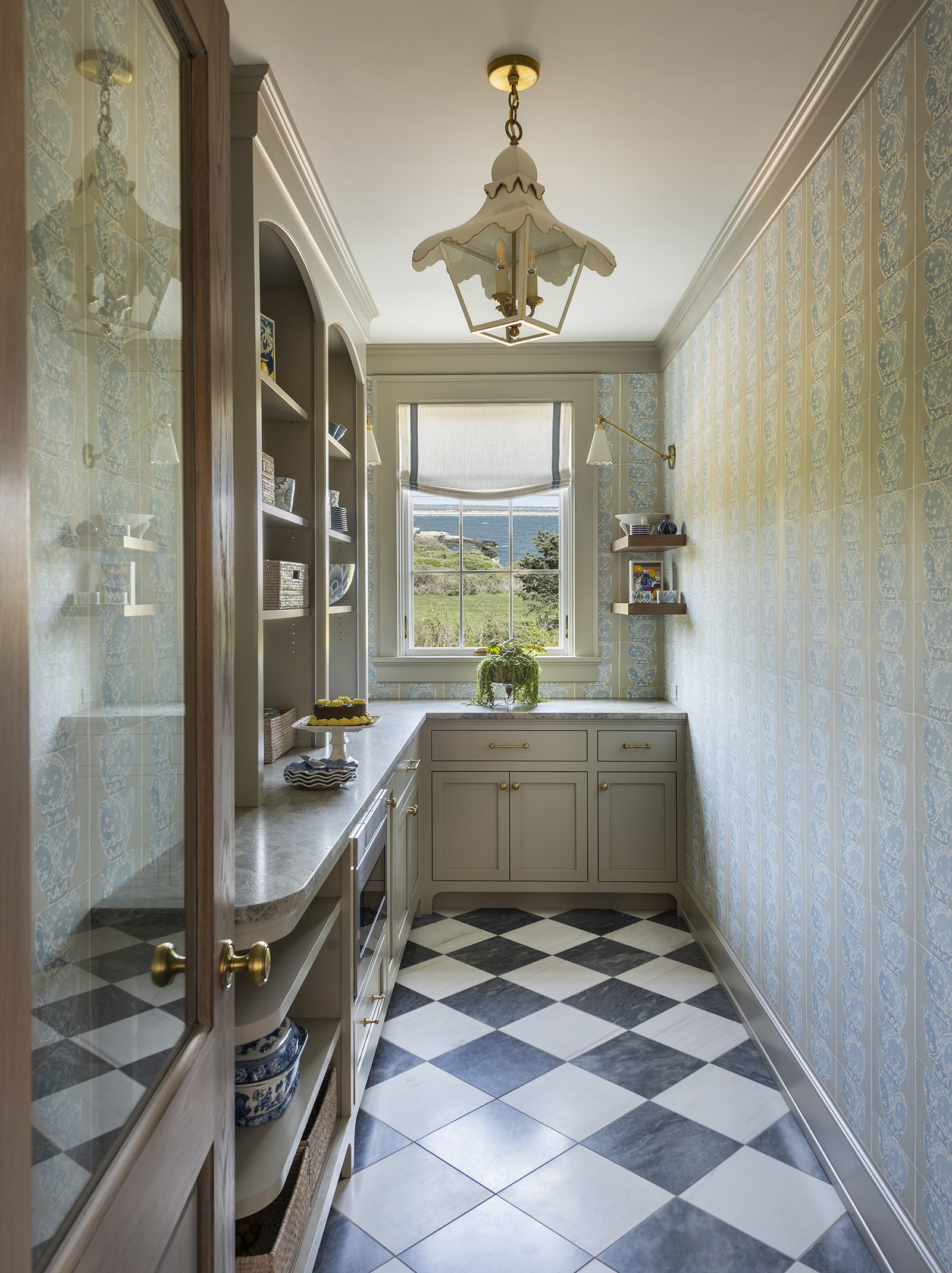 A butler's pantry scullery with checkerboard tile floor and wallpaper in a coastal home designed by Taste Design, Newport RI