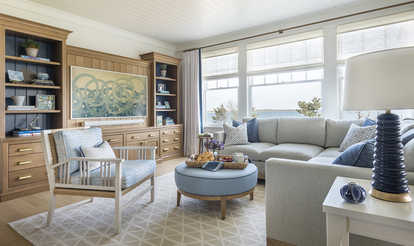 A blue and white family media room with built in oak media center in a coastal home with interior design by Taste Design Inc of Newport RI