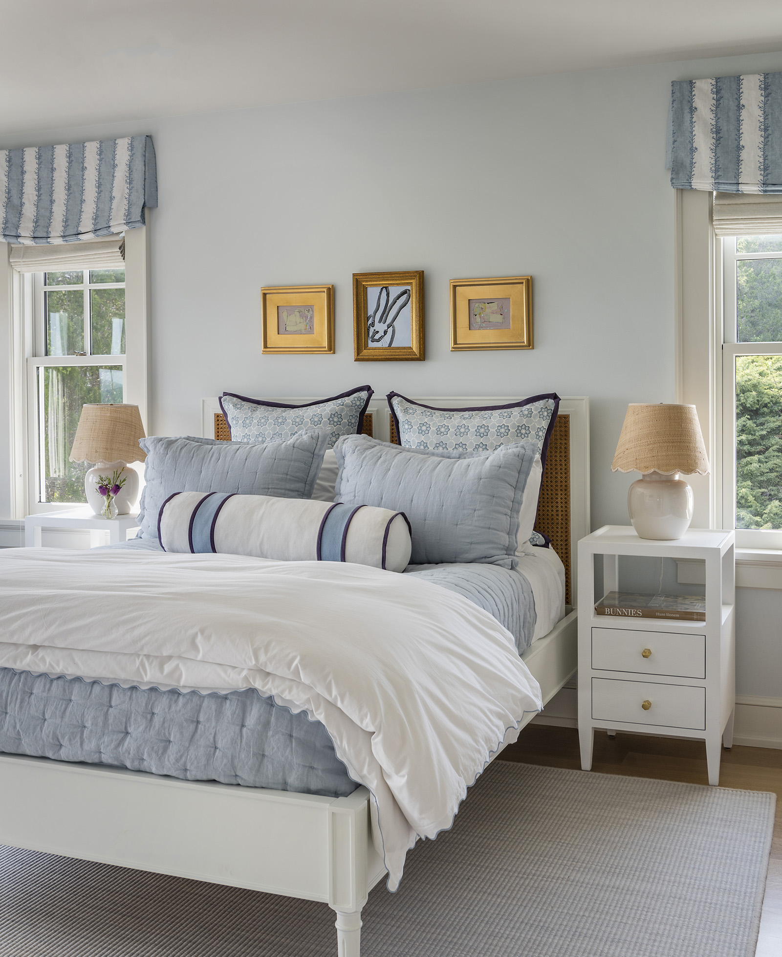 A blue and white bedroom with original art by Hunt Solnem in a modern coastal home designed by Taste Interior Design