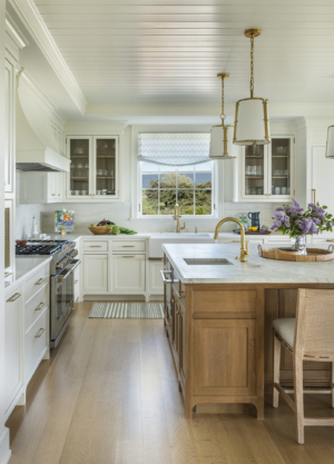 A white kitchen with large oak island designed by Taste Design in a modern oceanfront home near Newport RI