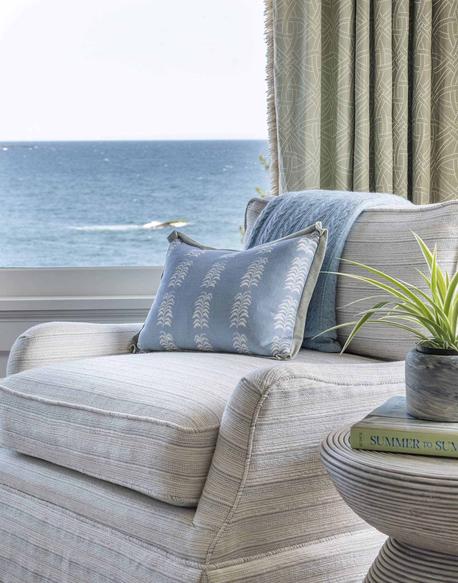A copy reading nook with an ocean view in the owner's suite of a modern coastal home designed by Taste Interior Design