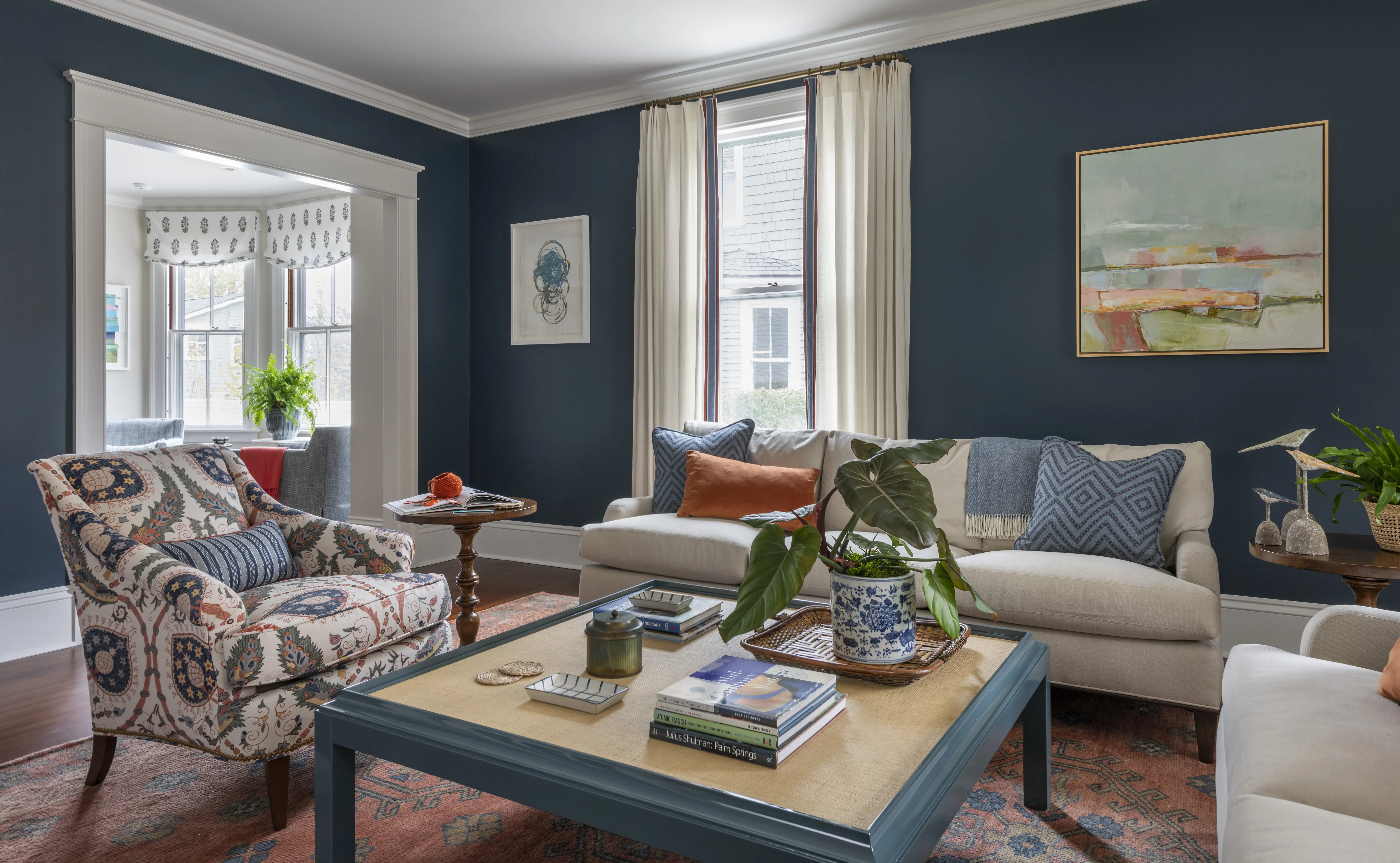 Living room designed by Taste with blue walls and vintage rug and large raffia coffee table