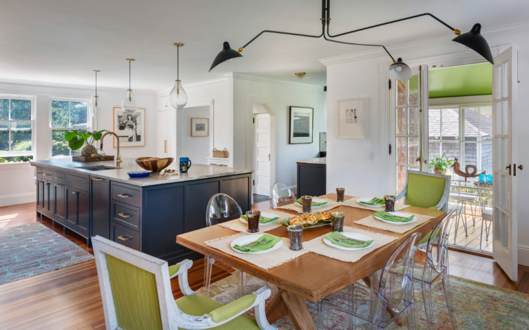 A dining room with greem host chairs and a modern light fixture