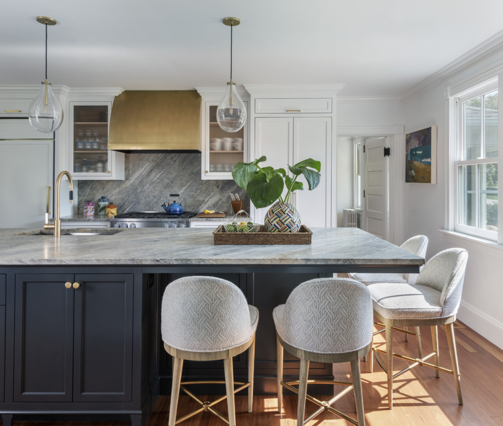 Chairs and a kitchen island with brass range hood and fixtures