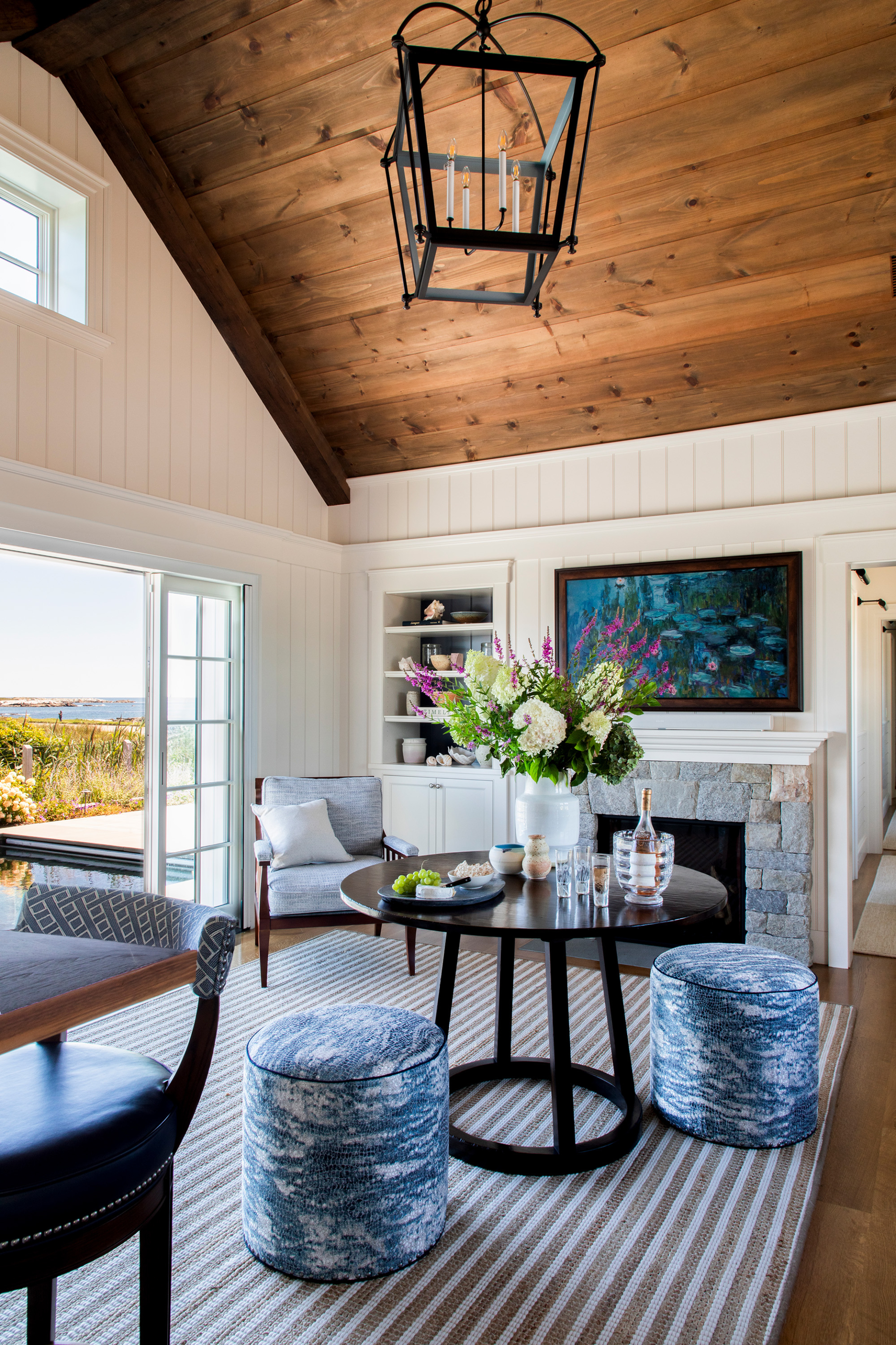 Elegant sitting room at Ocean Lodge featuring a natural stone fireplace, peaked wood ceiling, and interior design rooted in timeless coastal style