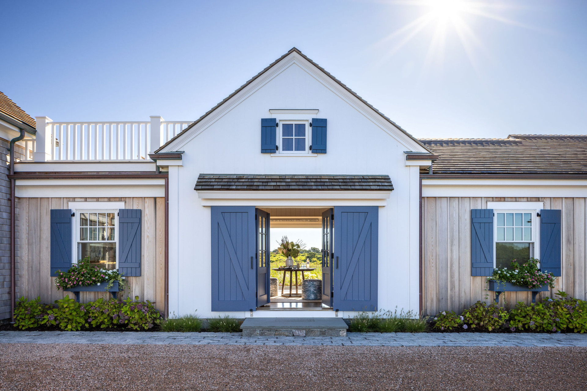 Front entry view of Ocean Lodge in Newport, showcasing restored architecture with blue shutters, vertical wood siding, and historic detailing by Taste Design Inc. and Patrick Ahearn.