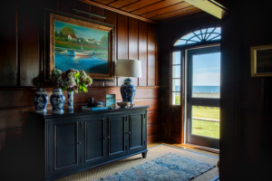 Entry hall vignette with nautical painting, blue chinoiserie vases, and wood paneling showcasing Newport’s rich residential design history.