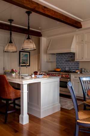 A coastal cottage kitchen with a blue tile backsplash and natural wood beams in the ceiling.