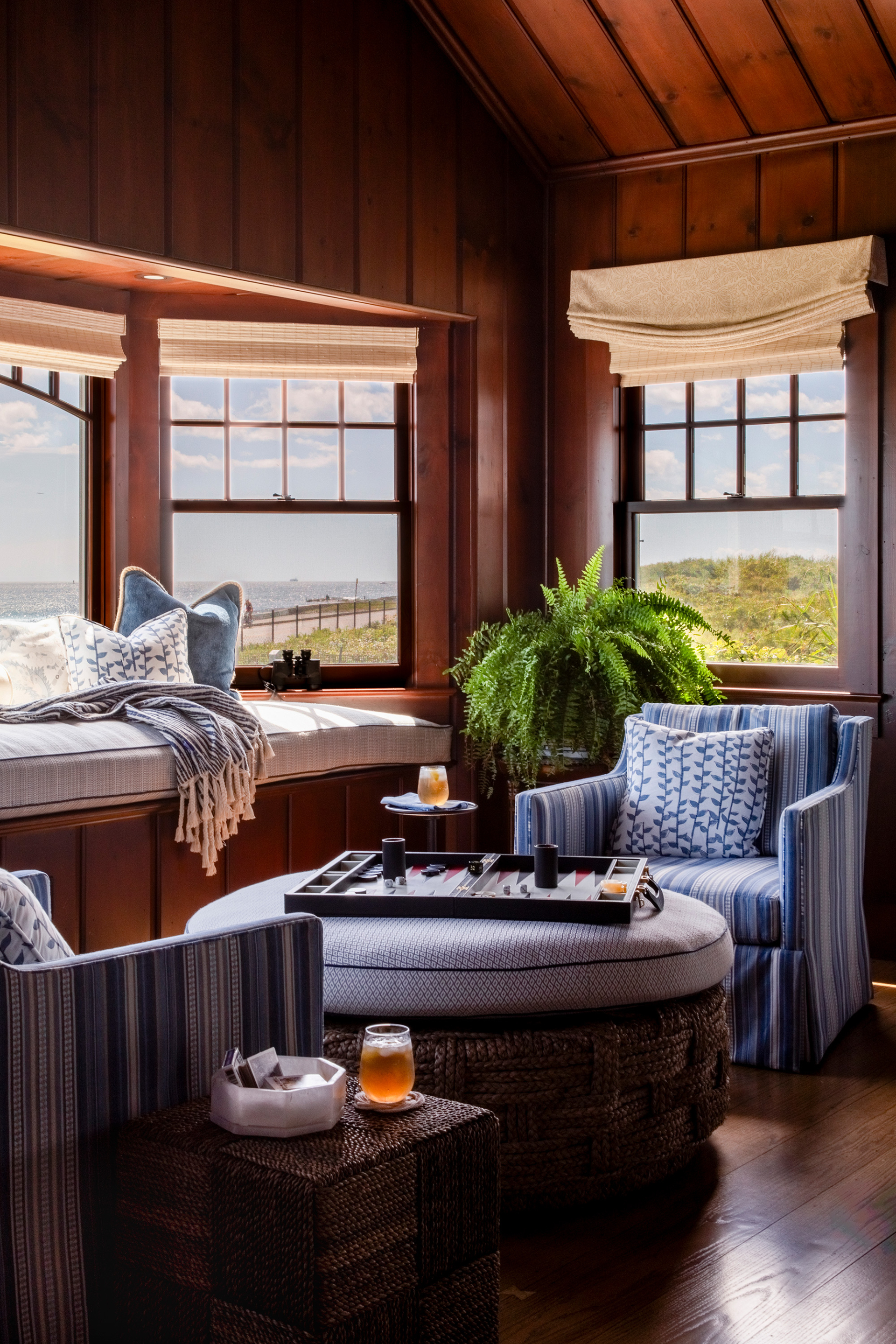 Ocean-facing game room with original wood paneling, custom window seat, and playful textiles, capturing the essence of coastal relaxation.