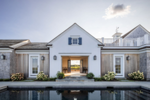 Ocean Lodge pool elevation with symmetrical white façades and barn doors opening to views, demonstrating seamless integration of original scale with coastal design updates.