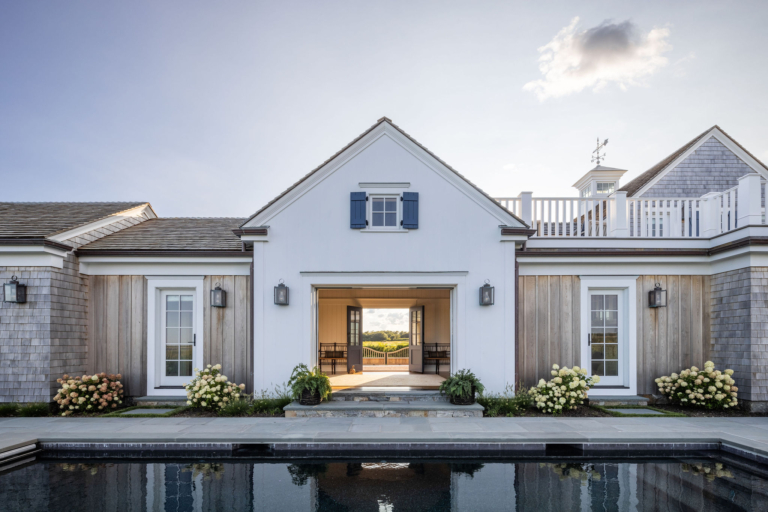 Ocean Lodge pool elevation with symmetrical white façades and barn doors opening to views, demonstrating seamless integration of original scale with coastal design updates.