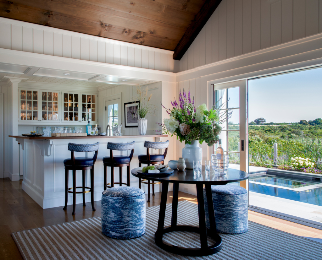 Indoor bar and seating area at Ocean Lodge overlooking the pool, with custom millwork and florals by Taste Design Inc. blending indoor comfort with outdoor beauty.
