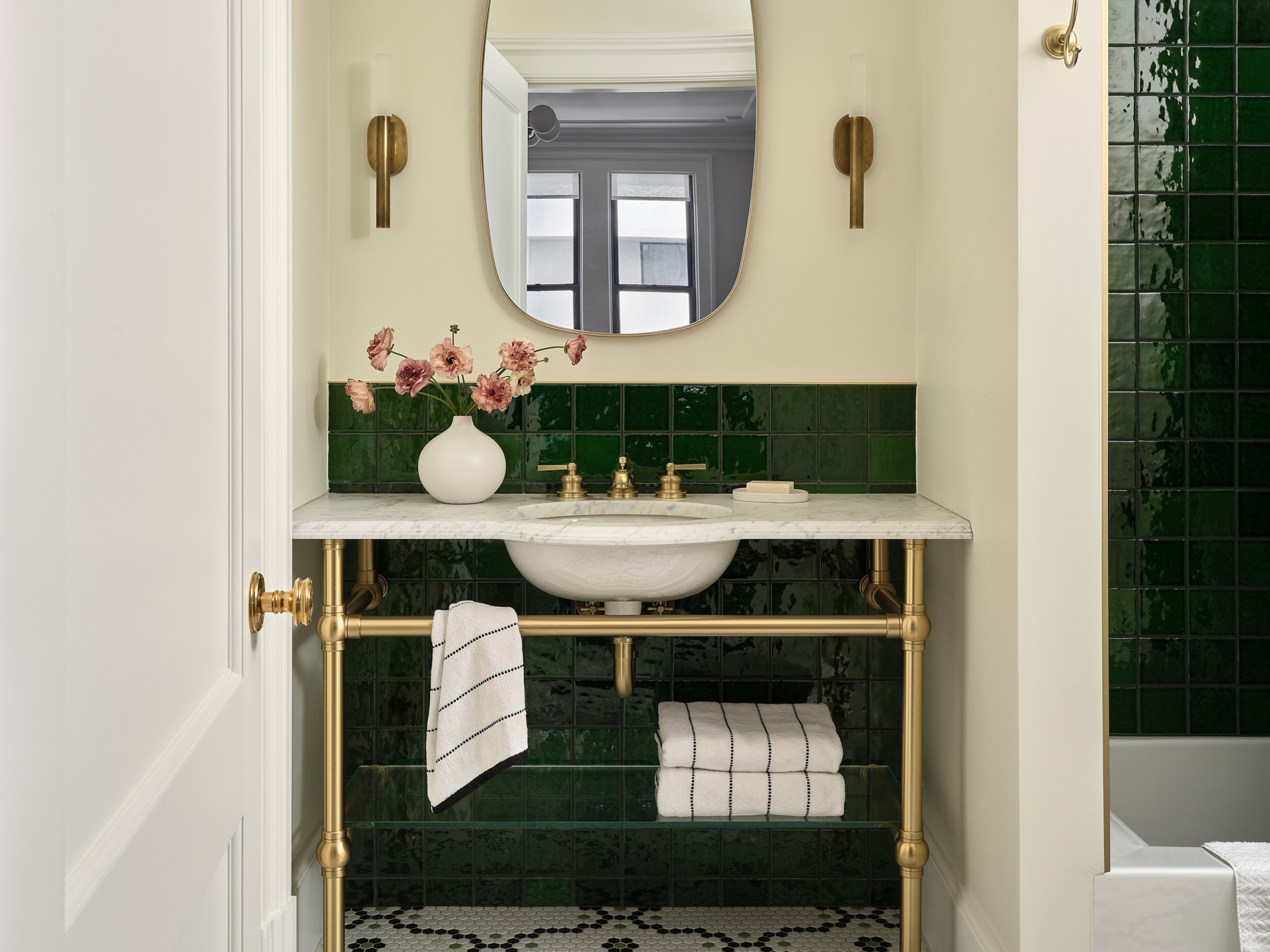 Close up of marble vanity with brass fixtures and floral arrangement in UWS apartment renovation.