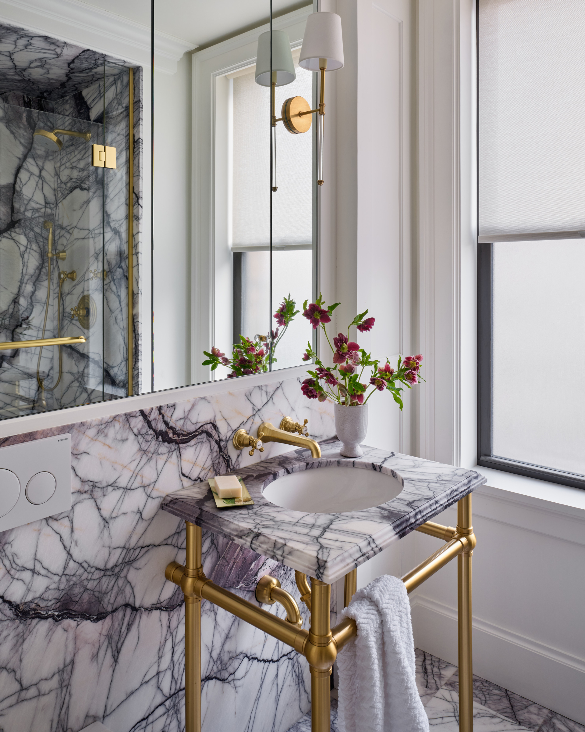 Detail of marble vanity with brass fixtures and flowers in UWS pet-friendly apartment renovation.