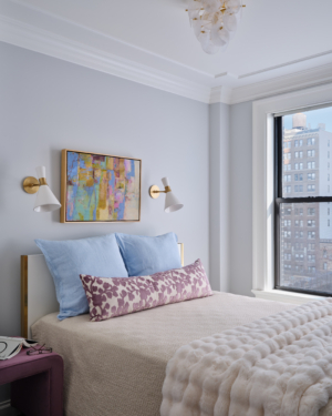 Bedroom with blue linen pillows, purple bench, and abstract artwork in Upper West Side apartment renovation.