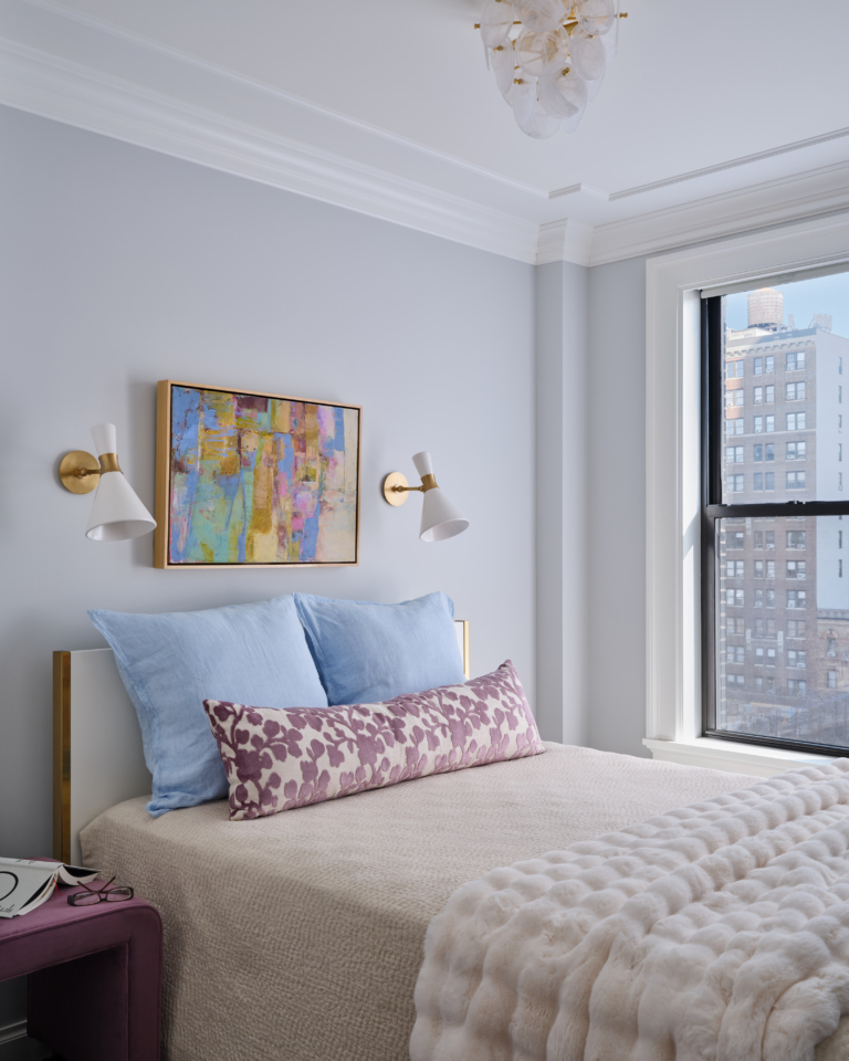 Bedroom with blue linen pillows, purple bench, and abstract artwork in Upper West Side apartment renovation.