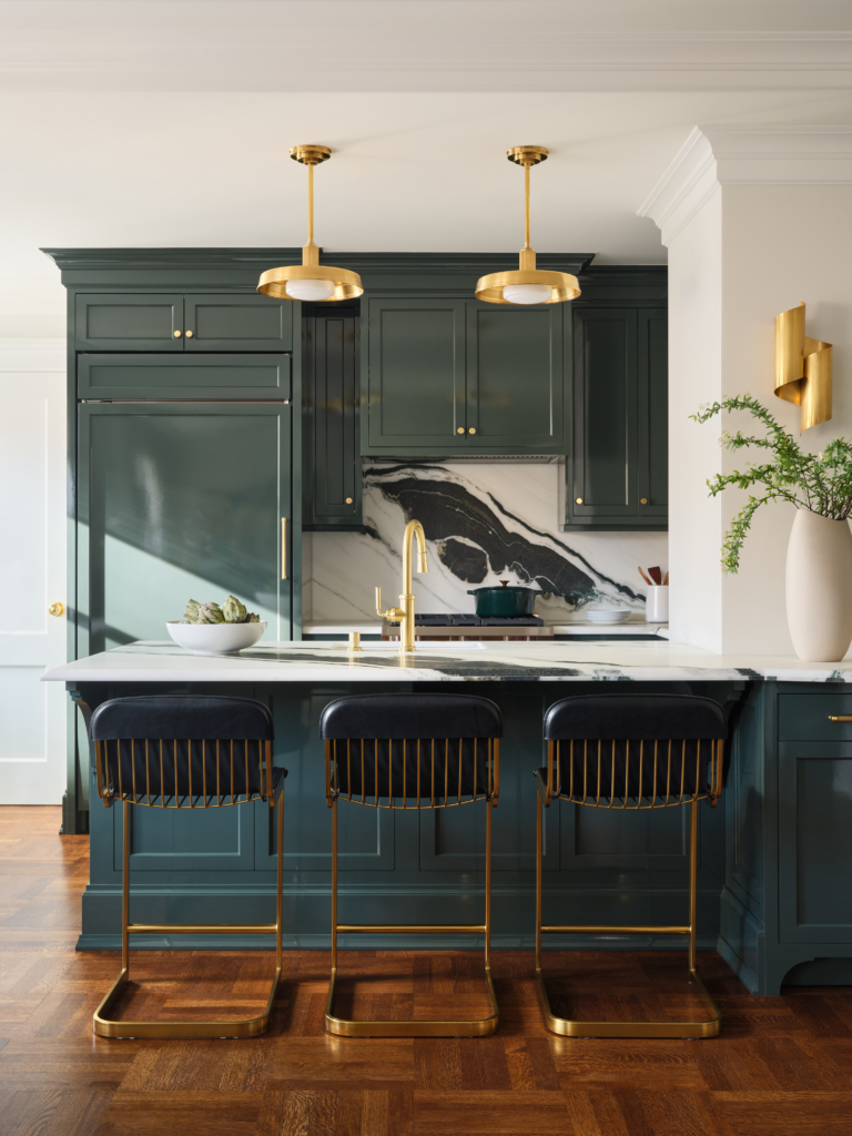 Marble island with brass lighting and navy cabinetry in Upper West Side apartment renovation by Taste Design Inc.