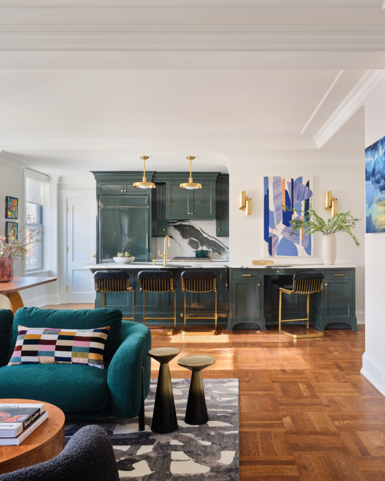 Open concept living room and kitchen with dark green cabinetry and bold artwork in UWS apartment renovation by Taste Design Inc.