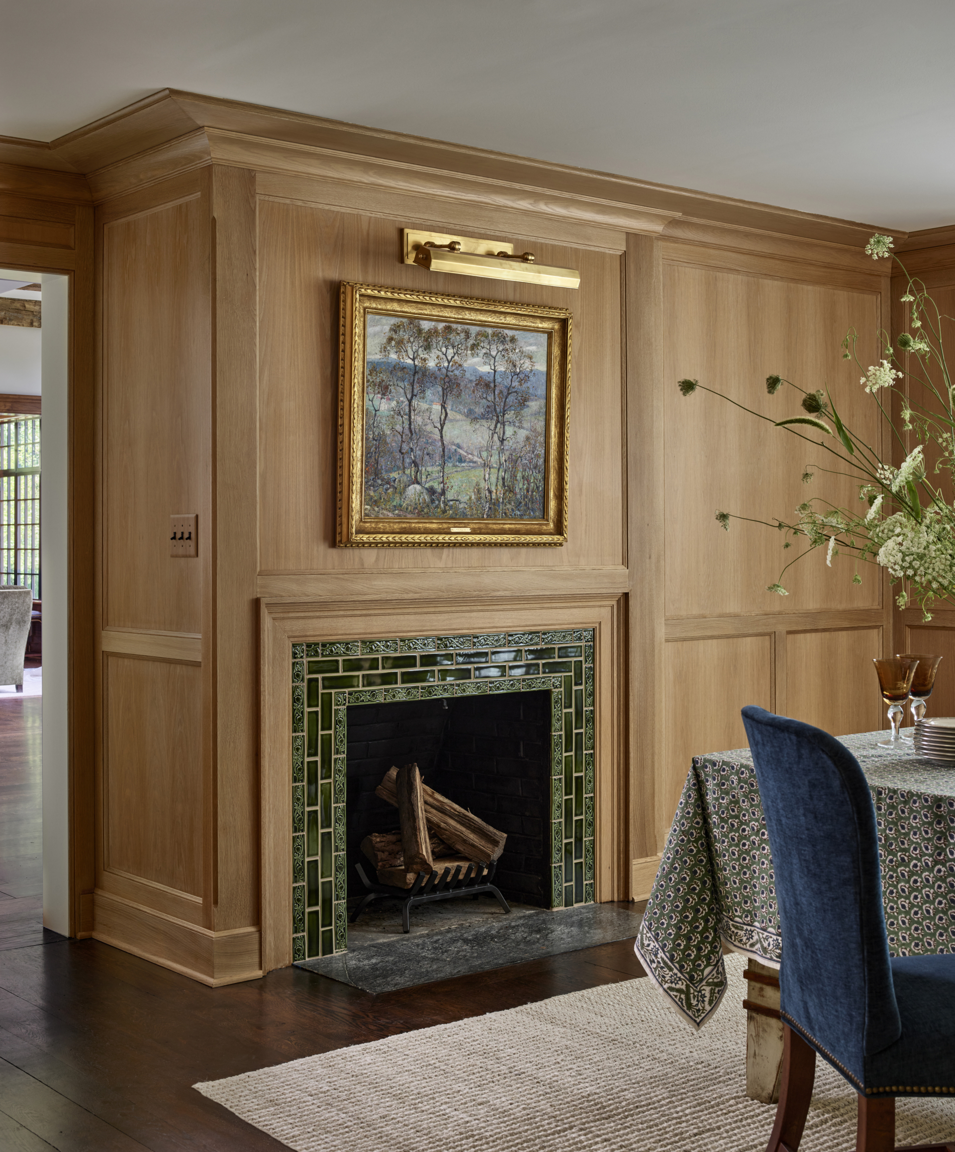 Dining Room fireplace with a green tile surround in a oak paneled room