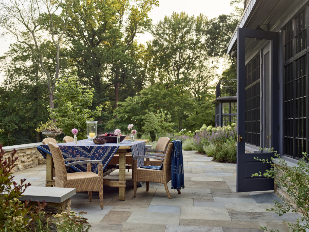 A patio dining table set with a blue table cloth and flowers