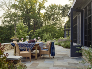 A patio dining table set with a blue table cloth and flowers