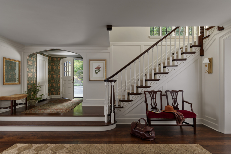 A front entryway with William Morris wallpaper and antique bench