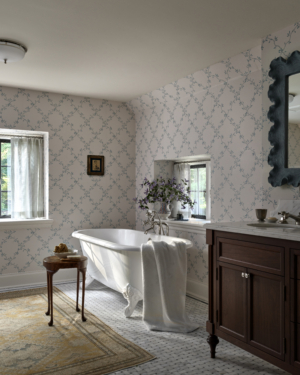 A bathroom with blue and white wallpaper and a clawfoot tub