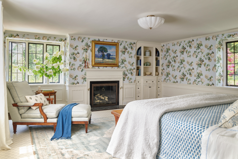 A primary bedroom with floral wallpaper and a fireplace