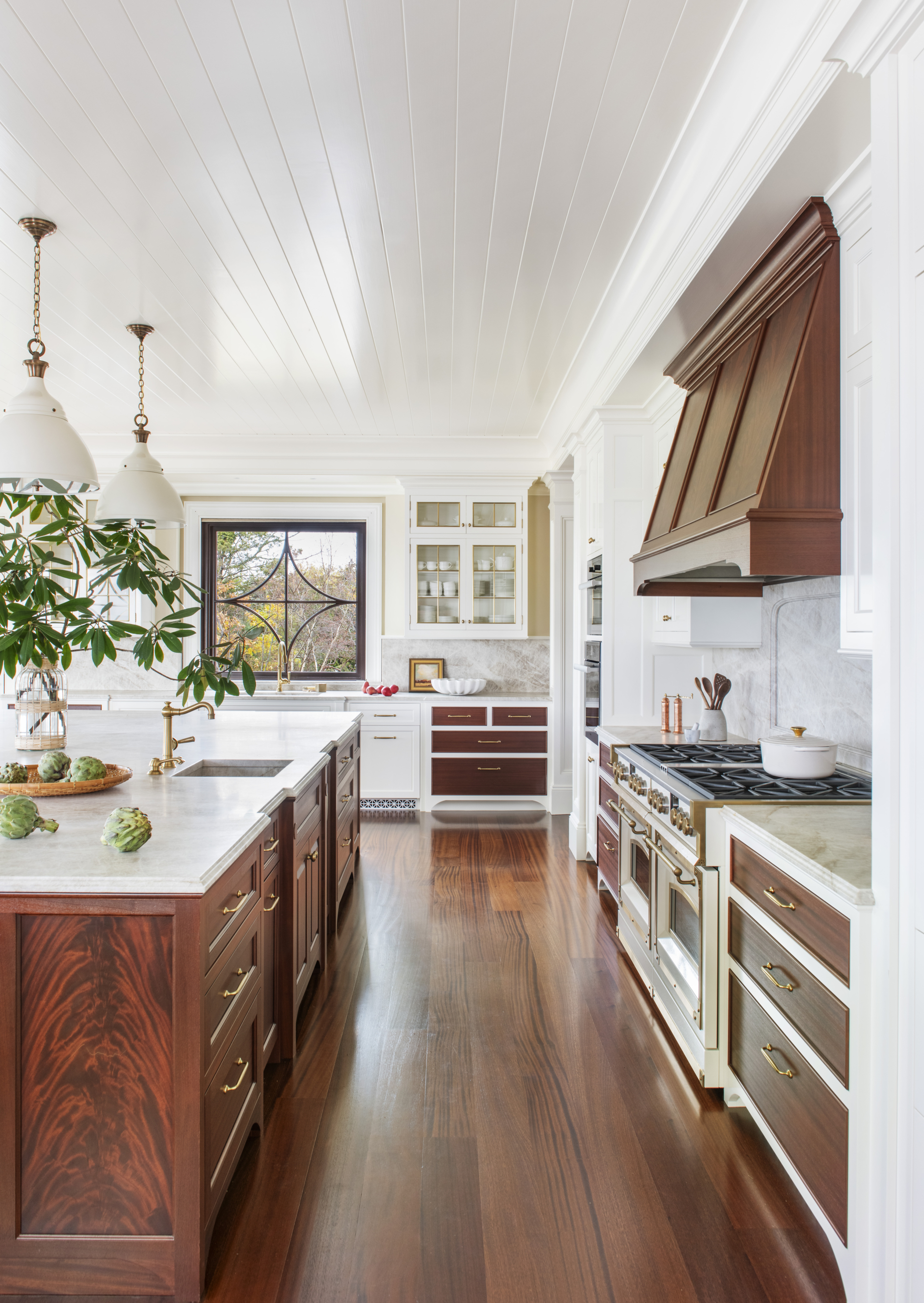 A luxury white kitchen with a mahogany island and hood.