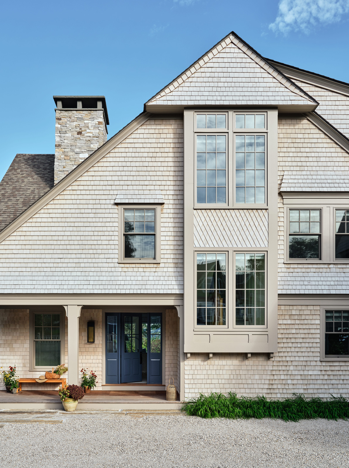 The front elevation of a contemporary shingle-style home with blue front door.