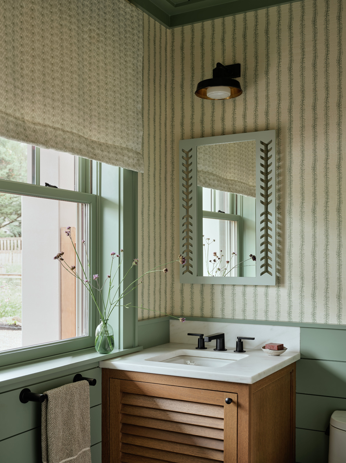 A green powder room with an oak vanity.