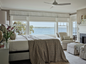 A coastal, neutral bedroom with fireplace.