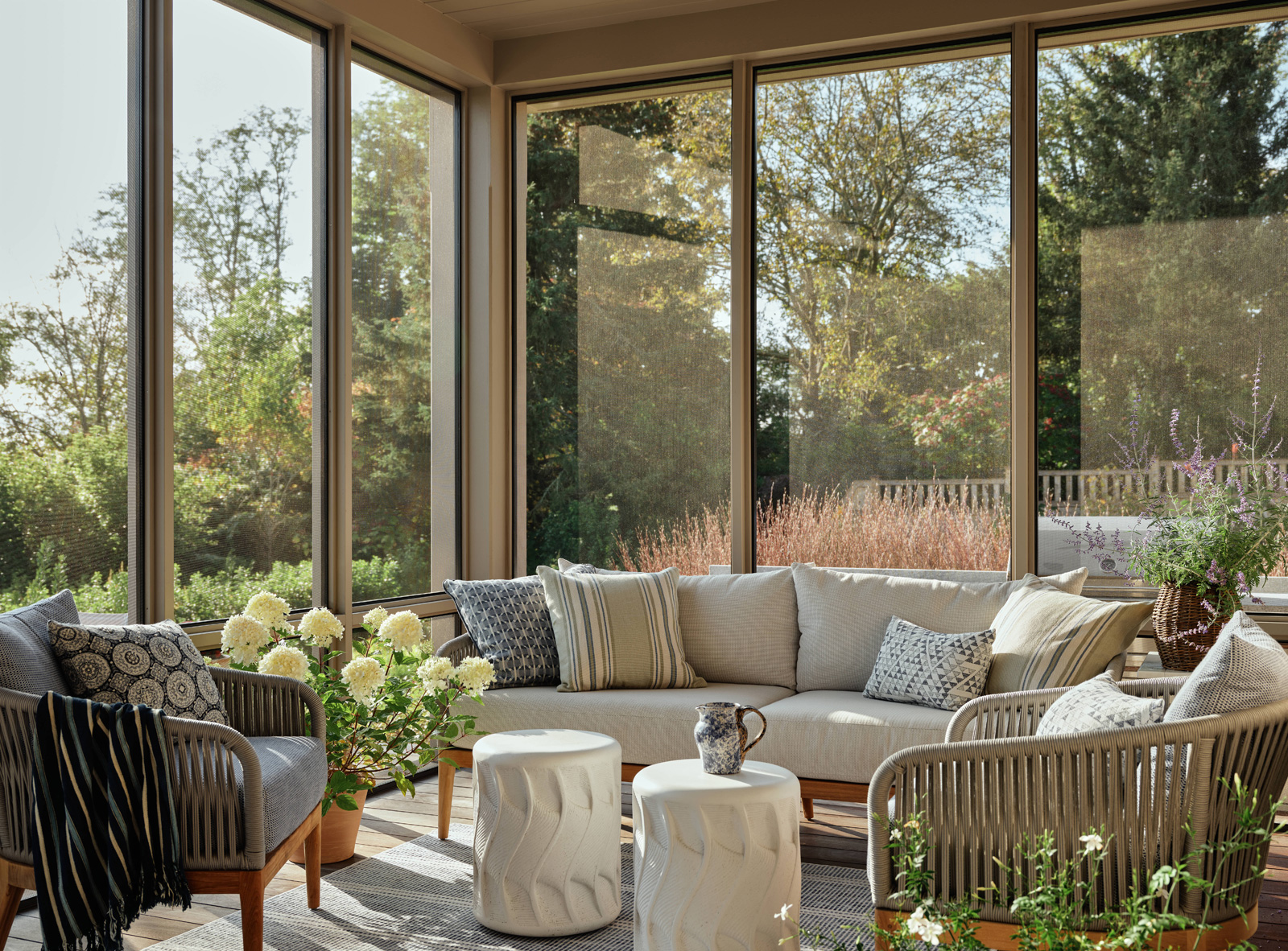 A screened in porch with outdoor seating and garden stools.