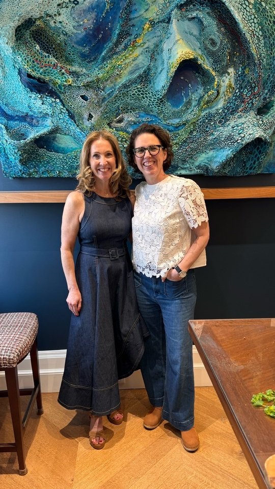 Amy Genser and friend stand in front of Amy's artwork